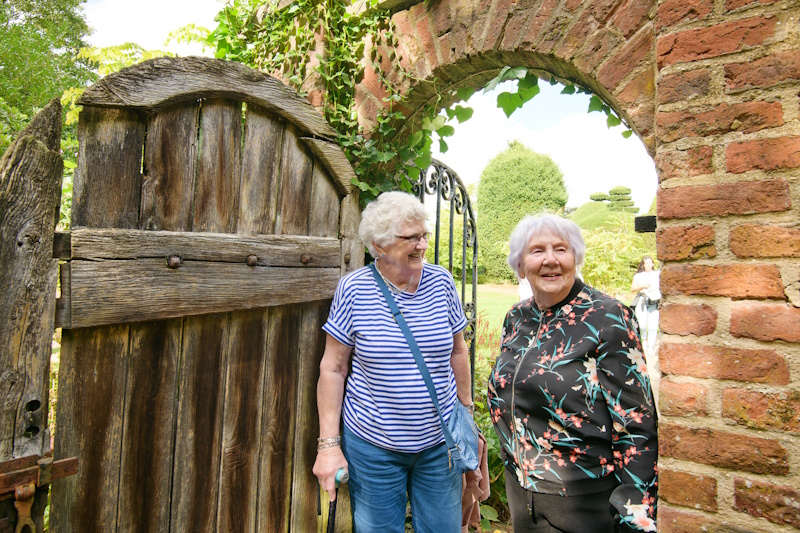 Two women walking through an outside arched doorway