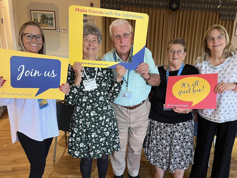 Five people with Friendship Month placards smiling