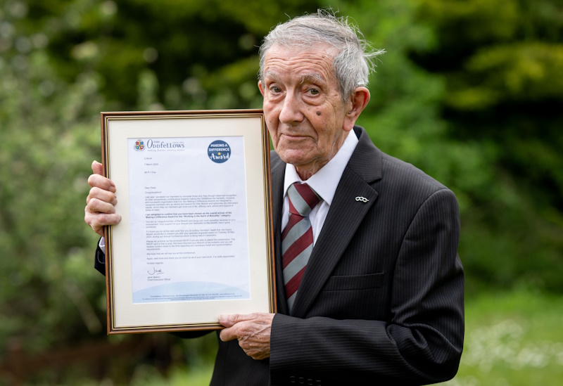 Peter Coe holding a framed letter