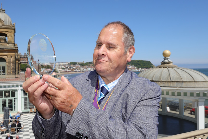 A man looks at a glass trophy
