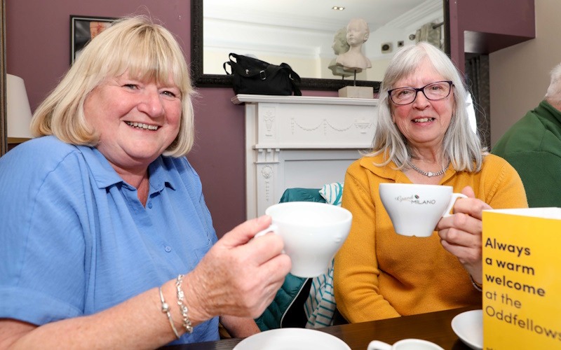 Two women with coffee cups raised