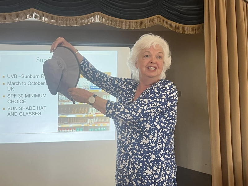 Marie holding up a sun hat as part of a talk she is giving to fellow members