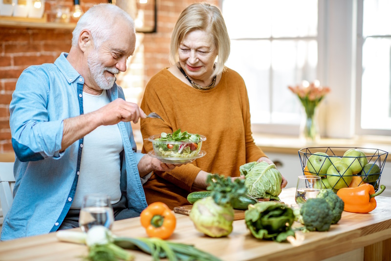A man and a woman making a salad with healthy ingredients