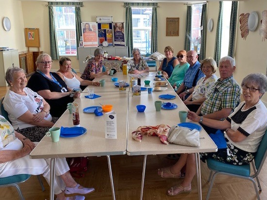 12 people sitting round a table smiling at the camera