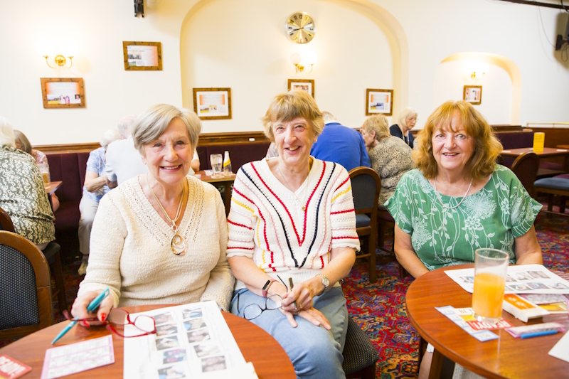 Three women members at a social event in a pub setting. They are looking at the camera and smiling.
