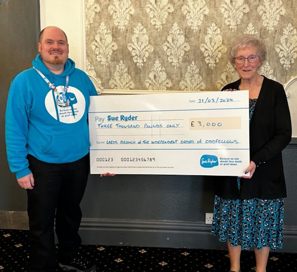 A man and a woman hold up a large cheque for £3,000