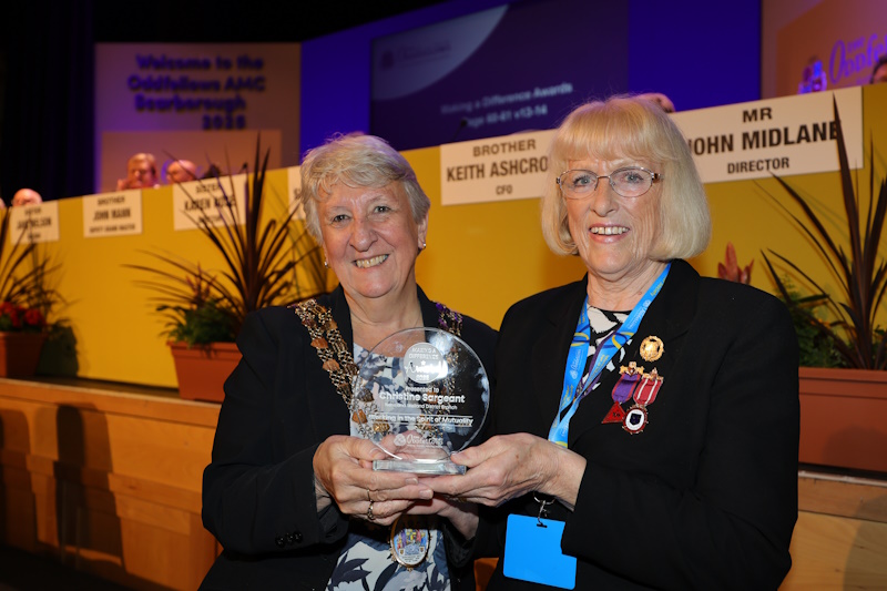 Two women holding a glass trophy together