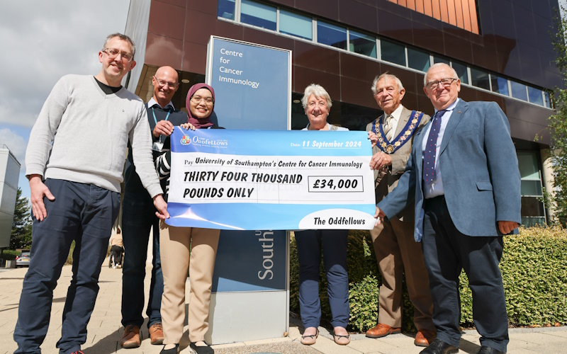Six people hold a large cheque for £34,000