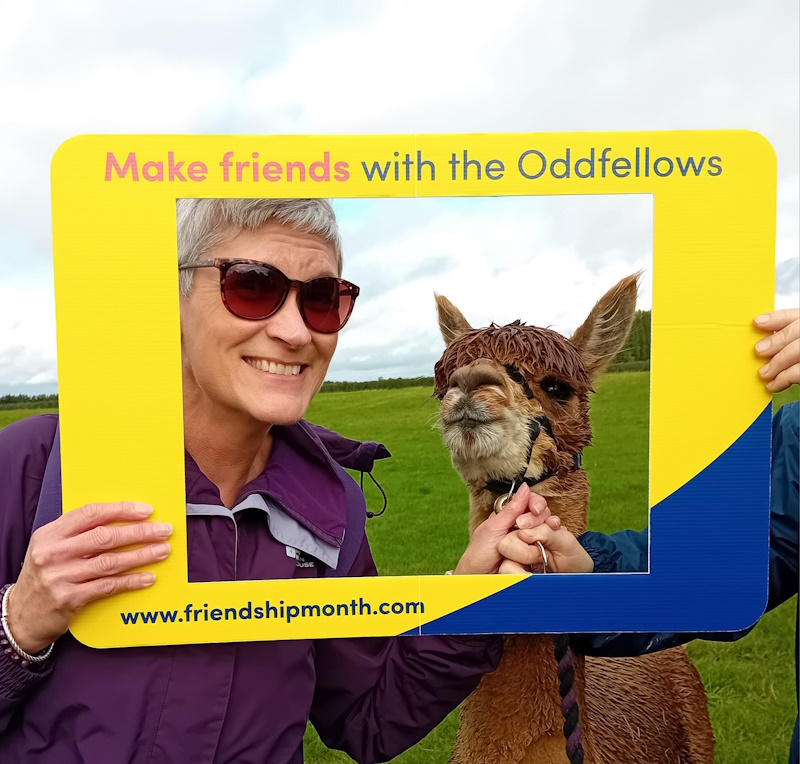 A woman smiling next to an alpaca