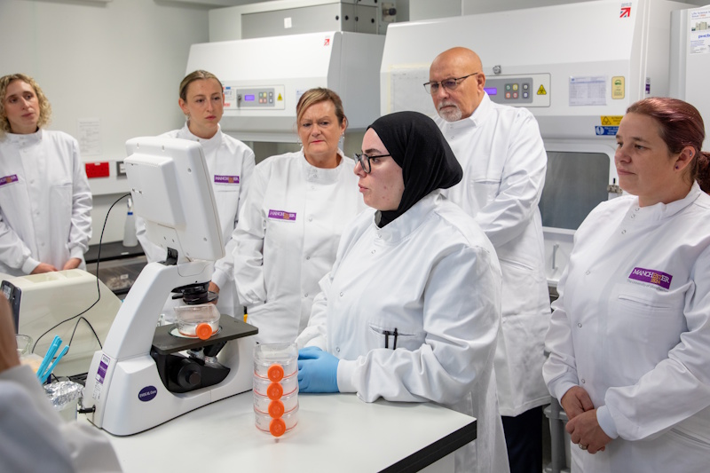 People in lab coats looking at a monitor